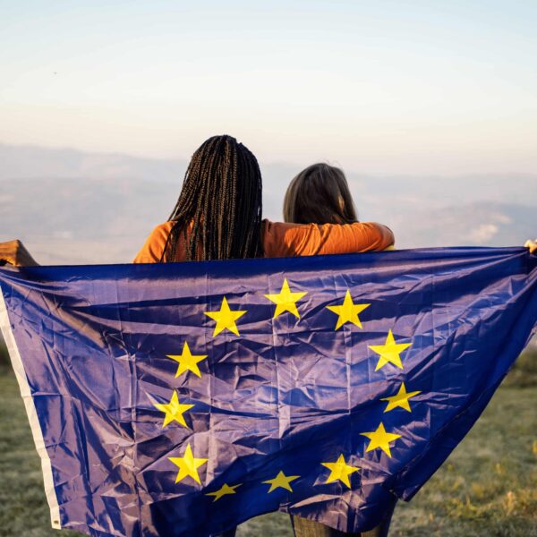 Zwei Frauen halten die EU Flagge und schauen in die Ferne.