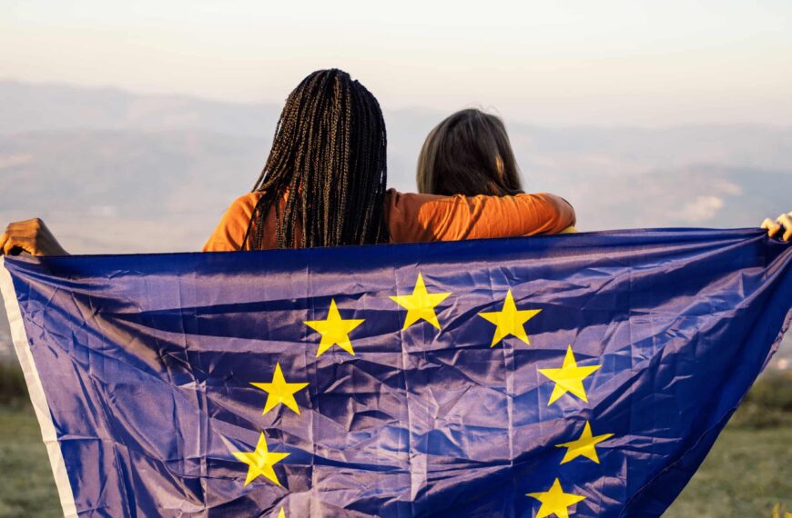 Zwei Frauen halten die EU Flagge und schauen in die Ferne.